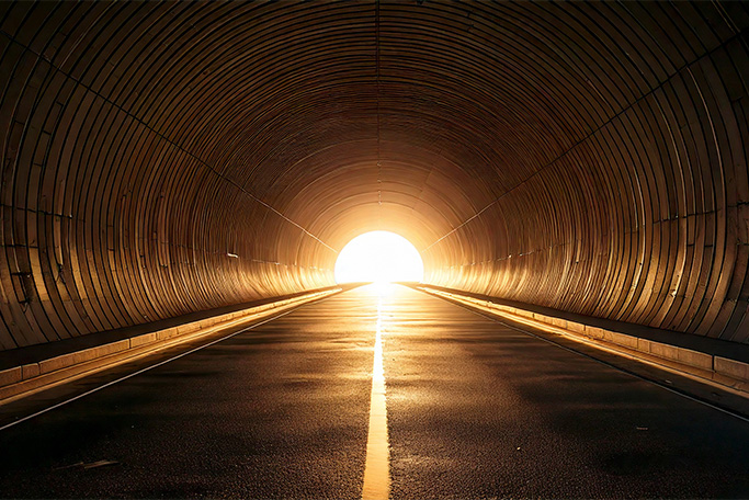 暗いトンネルの出口から明るい光が射している